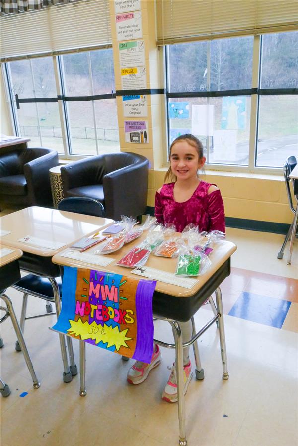 girl sitting at desk with mini notebooks for sale